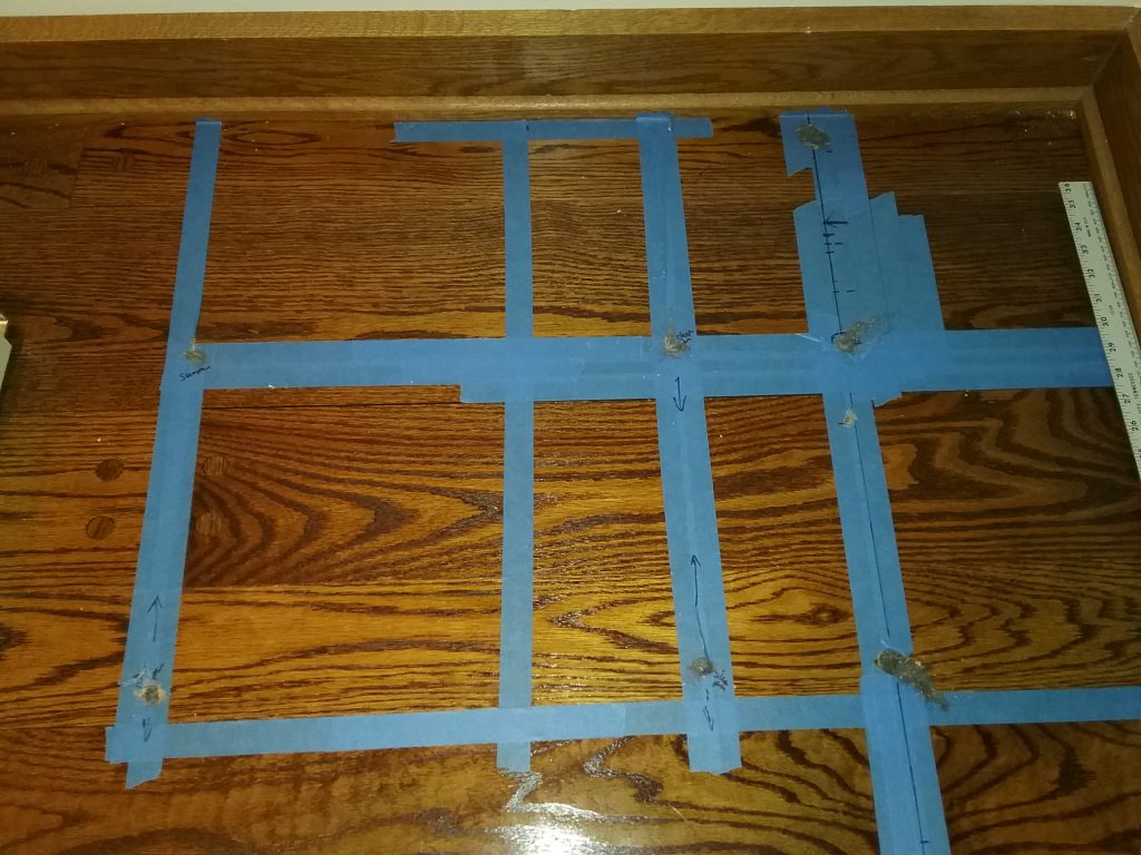 Blue tape grid to help us find sleepers. We drilled 5 holes before striking the first sleeper. The additional 3 holes confirmed the east-west orientation of the sleepers. The Charles A. Weyerhaeuser Memorial Museum, 2019.