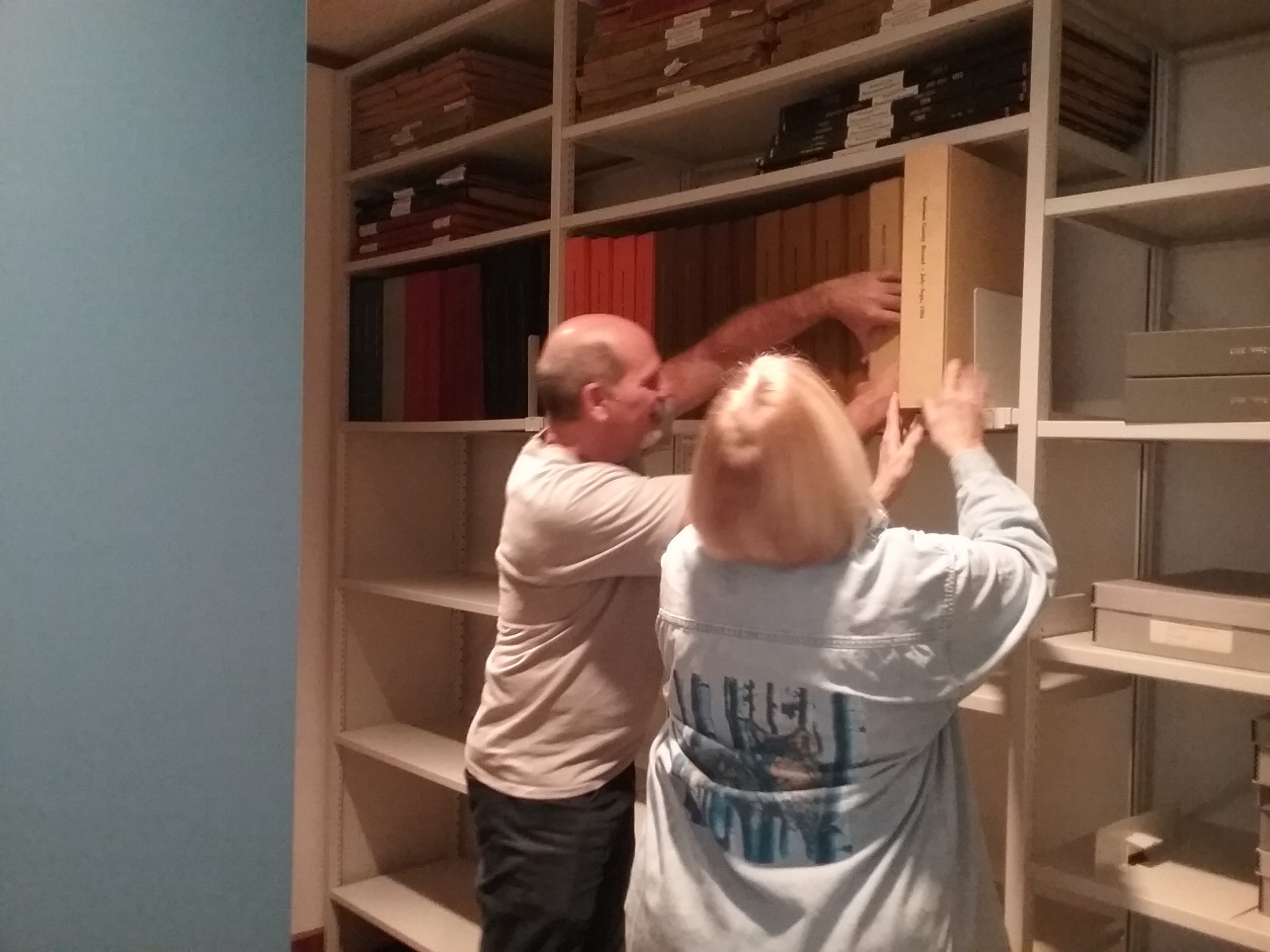 Gary and Pat putting volumes of the Morrison County Record on new mobile shelving in the Archives at the Weyerhaeuser Museum, December 21, 2019.