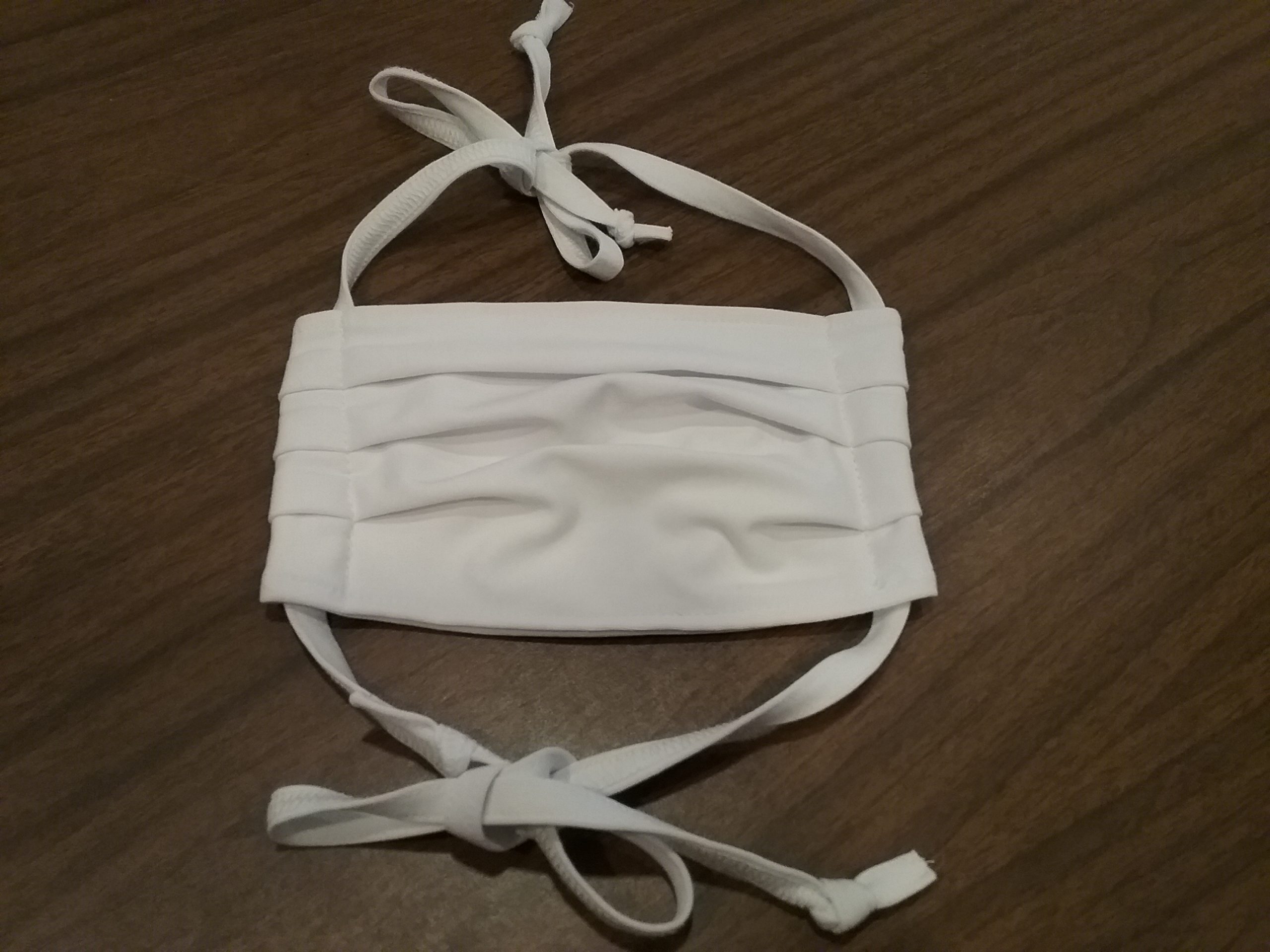 White, pleated cloth mask for COVID-19 pandemic, January 2021.
