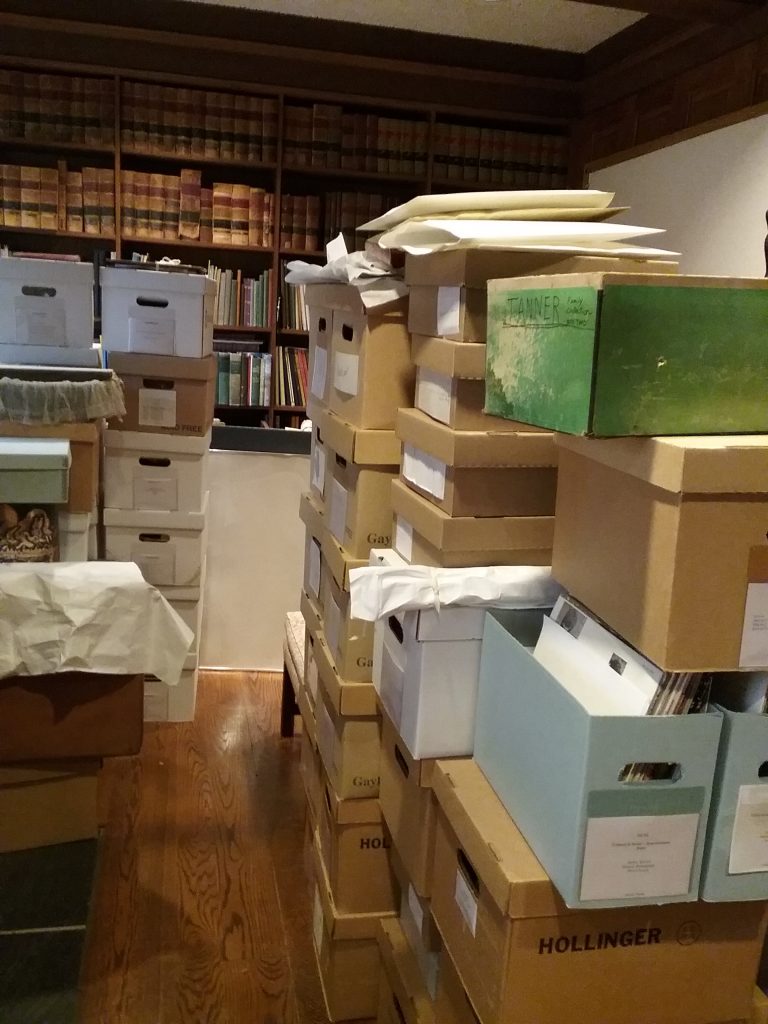 Boxes of collections items temporarily stacked in the R.D. Musser Library at The Charles A. Weyerhaeuser Memorial Museum, Little Falls, MN, in advance of the replacement of the HVAC system. Photo taken October 2, 2021.